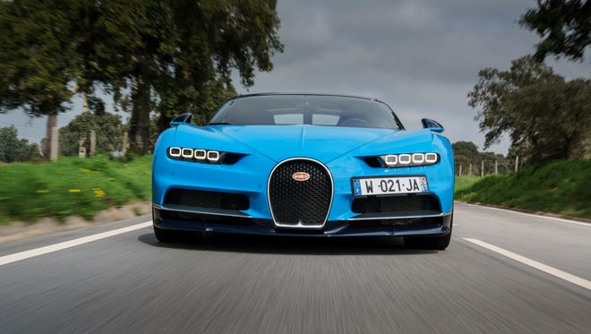 The front end of a Bugatti Chiron driving down a country road.