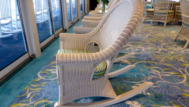 A line up of wicker rockers looks out onto the open deck from the aft portion of the Sky Lounge.