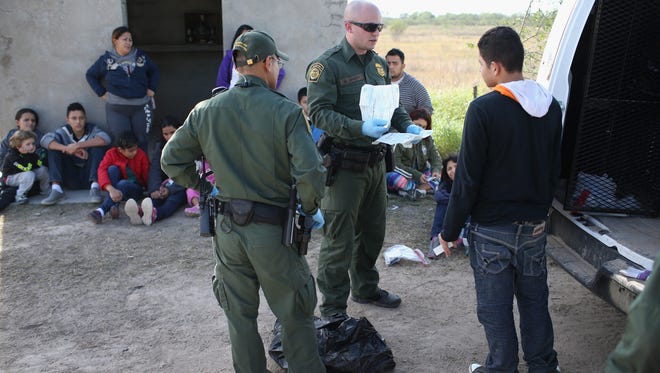 A U.S. Border Patrol agent checks a Central American migrant's documents on Dec. 8, 2015 near Rio Grande City, Texas. A group of immigrants had just illegally crossed the United States-Mexico border into Texas to seek asylum in the United States. The number of migrant families and unaccompanied minors has again surged in recent months, even as the total number of illegal crossings nationwide has gone down over the previous year.