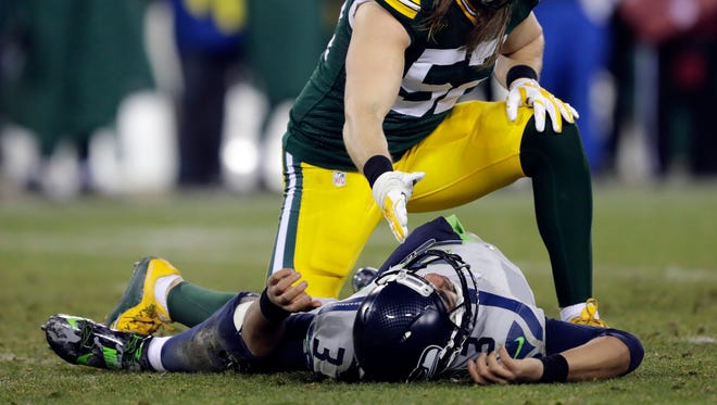 Packers player Clay Matthews offers a helping hand to Seahawks quarterback Russell Wilson after knocking him to the ground in the fourth quarter.