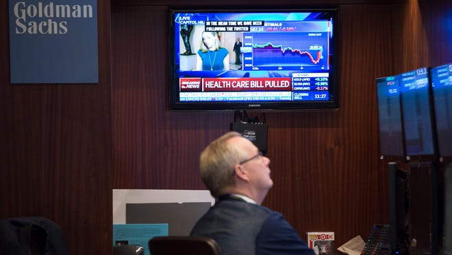 A TV show broadcasts that the Health Care Bill vote was pulled as traders work on the floor before the closing bell of the Dow Jones at the New York Stock Exchange, March 24, 2017 in New York.  (AFP PHOTO / BRYAN R. SMITH/AFP/Getty Images )