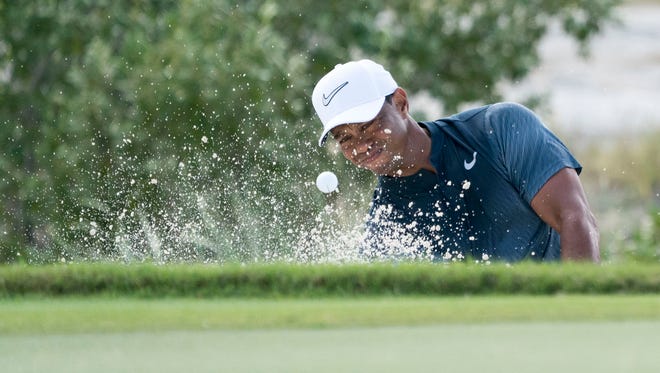 Tiger Woods hits out of the bunker on the fifth hole during the third round of the Hero World Challenge golf tournament at Albany.