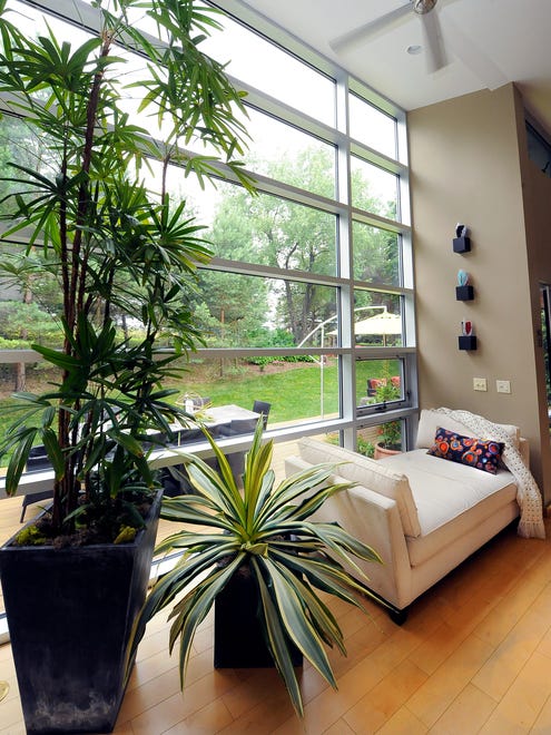 A chaise lounge affords a nice place to curl up and relaxnext to a wall of windows looking out onto the side yard. Large plants also help bring the outdoors in.