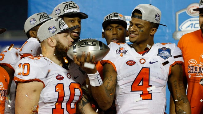 Clemson linebacker Ben Boulware (10), quarterback Deshaun Watson (4) and teammates celebrate with the championship trophy after the Tigers defeated Virginia Tech in the ACC title game.