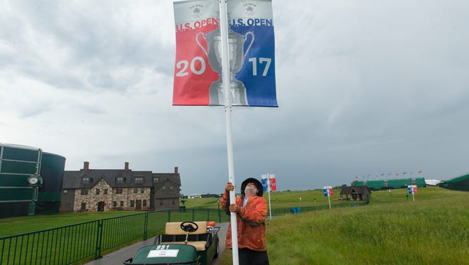 Course worker Jerry Smith erects a U.S. Open banner after strong storms passed through the area  at Erin Hills.
