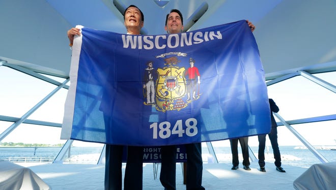 Gov. Scott Walker (right) and Foxconn Technology Group Chairman Terry Gou hold a Wisconsin flag at the Milwaukee Art Museum on July 27 to celebrate Foxconn's $10 billion investment to build a display panel plant in Wisconsin that could employ up to 13,000 workers and draw up to $3 billion in subsidies from state taxpayers.
