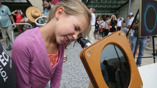 Isabelle Rostagno, 9, looks at the eclipse through one of the telescopes at the event.