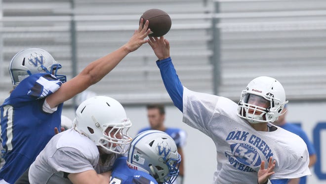 Oak Creek QB Jakup Sinani puts up a pass as a Waukesha West defender gets his hand on the ball.