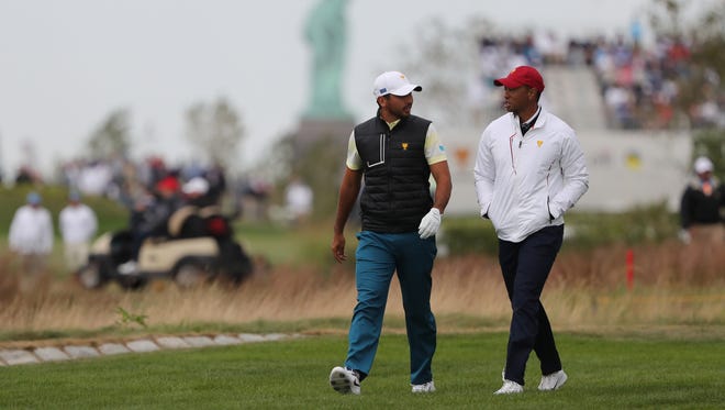 Jason Day (left) talks with assistant captain Tiger Woods while walking near the 12th hole during the fourth round four-ball matches of The President's on Sept. 30.