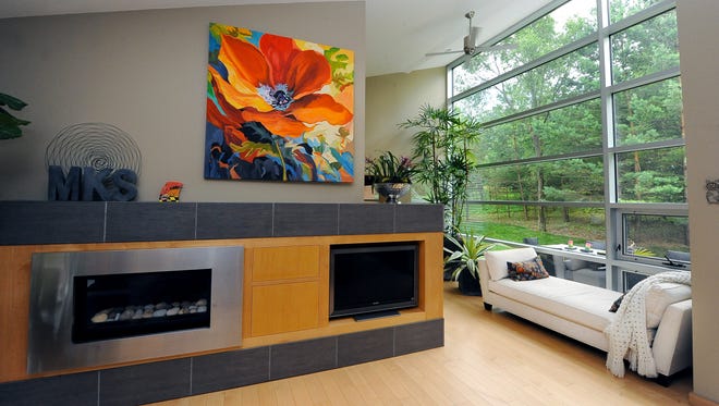 A large bank of windows blends the outdoors with the indoors with accents of plants, art and wood floors and furniture.