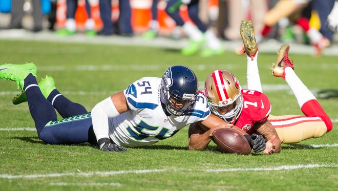 49ers quarterback Colin Kaepernick (7) dives after a fumble with Seahawks linebacker Bobby Wagner (54) during the first quarter.