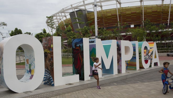 Children play near the Olympic Park sign in Rio de Janeiro, Brazil, where about $12 billion was spent to organize the 2016 games, which were plagued by cost-cutting, poor attendance, and reports of bribes and corruption linked to the building of some Olympic-related facilities.