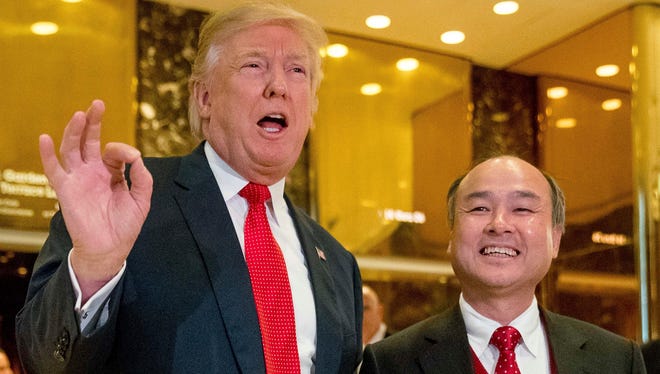 Then president-elect Donald Trump, left, accompanied by SoftBank CEO Masayoshi Son, speaks to members of the media at Trump Tower in New York.
