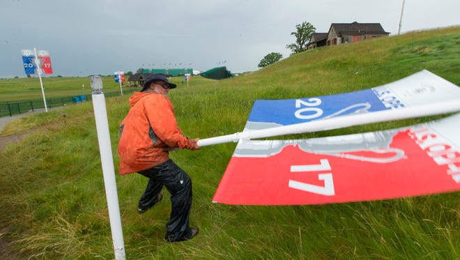 Course worker Jerry Smith erects a U.S. Open banner after strong storms passed through the area Tuesday at Erin Hills in Erin said it was the fifth times he has put the banners back up