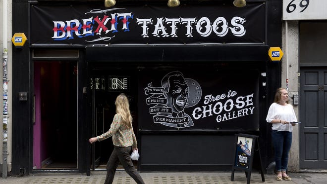 People walk past a pop-up "Brexit Tattoos" tattoo shop offering satirical anti-EU pro-Brexit tattoos for free, in central London on June 22, 2016. The shop, open for one day only, is the idea of the pro-EU "Remain" campaign.