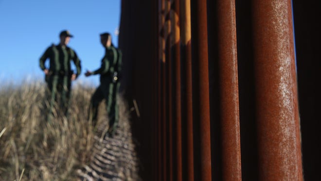 U.S. Border Patrol agents talk next to the United States-Mexico border fence on Dec. 9, 2014, near Nogales, Arizona.