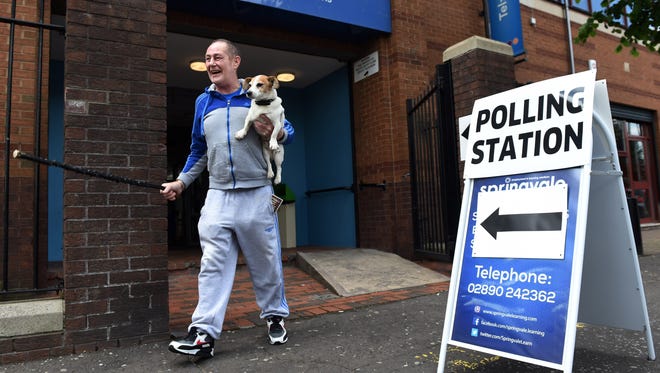 A man accompanied by his dog laughs as he exits a polling station after voting in the EU referendum in Belfast, Northern Ireland. The United Kingdom has gone to the polls to decide whether or not the country should remain within the European Union.