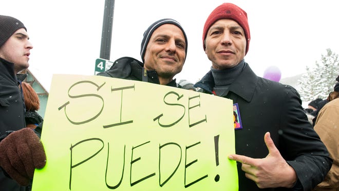 Peter Bratt, left, and Benjamin Bratt, right, participate in the Women's March on Main Street. The sign reads 'Yes you can!'