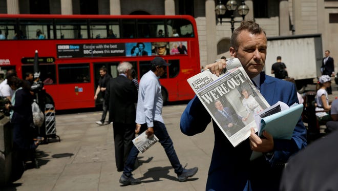 A journalist holds up a copy of the London Evening Standard newspaper as he takes part in a television broadcast outside the Bank of England in the City of London, on June 24, 2016