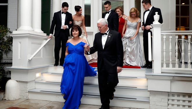 Vice President Mike Pence right, assists his wife Karen Pence as they depart the Naval Observatory for several inaugural balls,  in Washington.