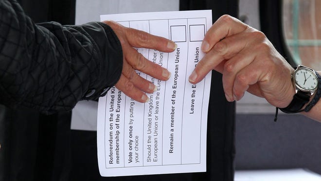 A volunteer hands an unmarked ballot paper to a voter inside a bus being used as a temporary polling station in Kingston-Upon-Hull, northern England, as Britain holds a referendum to vote on whether to remain in or to leave the European Union.