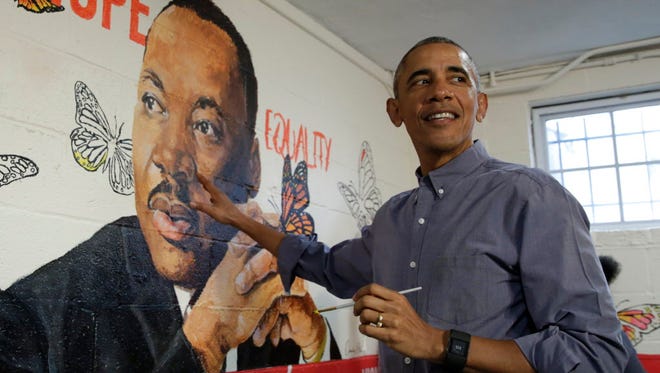Obama paints a mural with the residents at the Jobs Have Priority Shelter in Washington on Jan. 16, 2017.  The mural "Wall of Hope" was created by artist Omatayo Akinbolajo and features a painting of Martin Luther King Jr.