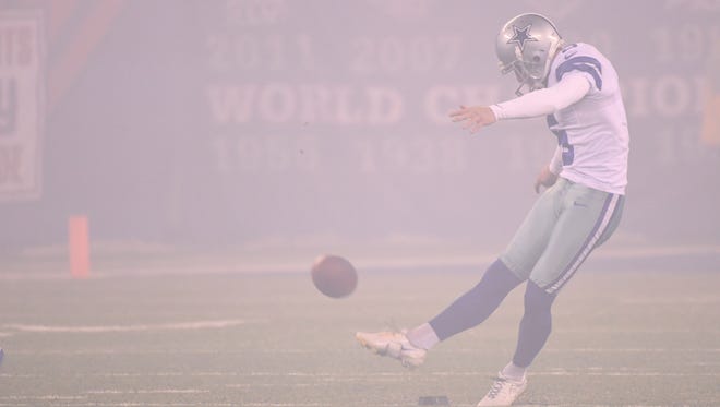 Cowboys kicker Dan Bailey (5) kicks off in the pregame smoke.