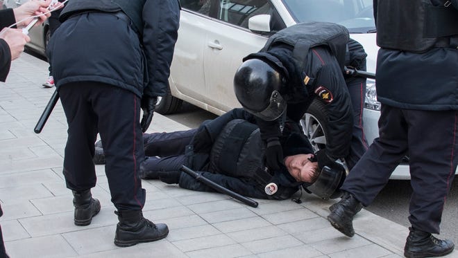 Police help a wounded comrade during fighting with protesters in Pushkin Square, in downtown Moscow on March 26, 2017.