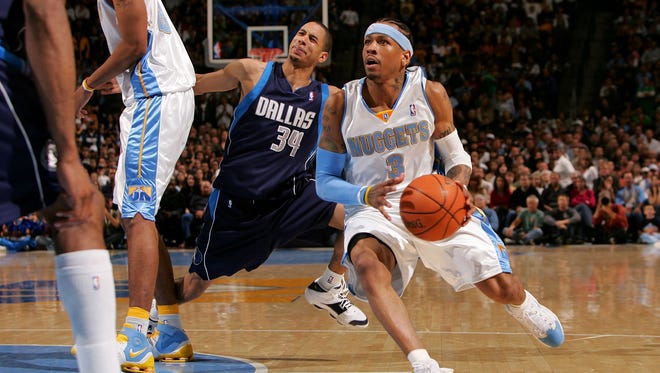Allen Iverson drives to the basket as Devin Harris falls victim to a pick by Marcus Camby.