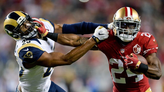 49ers running back Shaun Draughn (24) stiff-arms his way past Rams safety T.J. McDonald (25) on a first-half run.