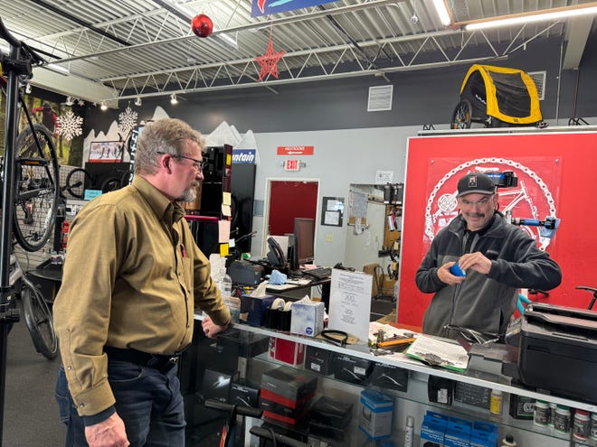 VeloCity Cycle owner Scott Hoggatt (left) and sales and repair leader Carlos Olivieri talk inside the business on March 12. Hoggatt plans to shut down the retail operations March 30 at the store, which faces Pewaukee Lake in the village.