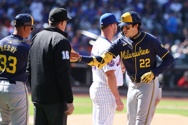 Brewers left fielder Christian Yelich slaps hands with first base coach Quintin Berry  after a single during the fifth inning.