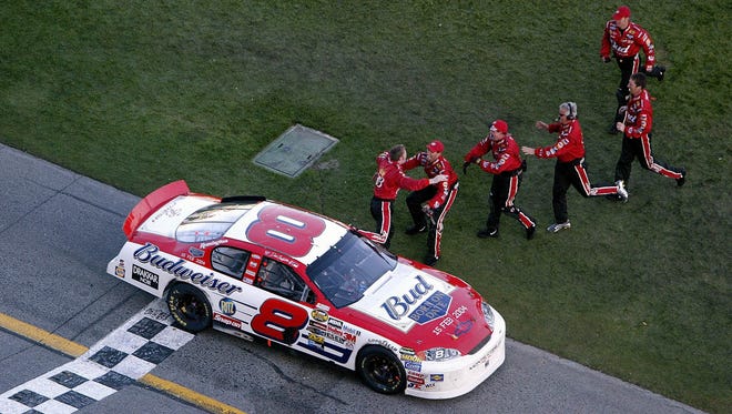 Crew members converge on Dale Earnhardt Jr., left, at the start-finish line after he won the 2004 Daytona 500, three years after his father died as a result of a last-lap crash in the 2001 event.