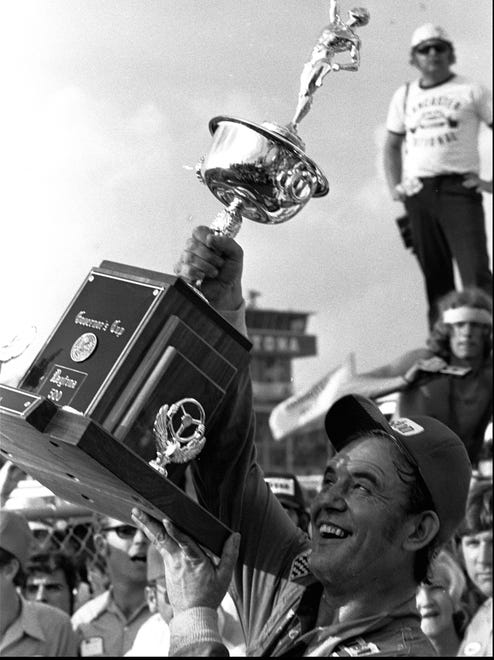 Former taxi cab driver Benny Parsons raises the championship trophy after winning the 1975 Daytona 500.
