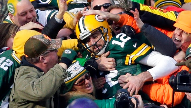 Green Bay Packers quarterback Aaron Rodgers (12) is swarmed by fans after scoring a touchdown in the first half during the game against Minnesota on Saturday, December 24, 2016 at Lambeau Field.